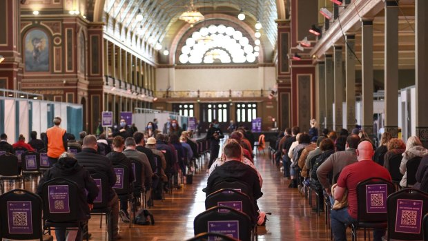 Victorians sit during the 15 minute waiting period after getting their vaccines at the Royal Exhibition Building in Melbourne.