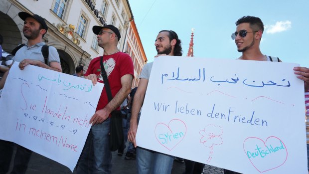 Refugees, some of from Syria, and their supporters demonstrate with posters saying "we love peace" and "they aren't acting in my name" in downtown Wuerzburg,after an axe attack on a local train.