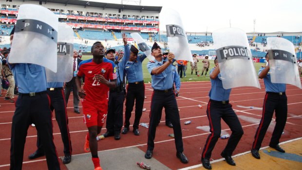 Intimidating: Police use shields to protect Panamanian Abdiel Arroyo from missiles thrown from the stands as he leaves the field at the Estadio Olimpico.