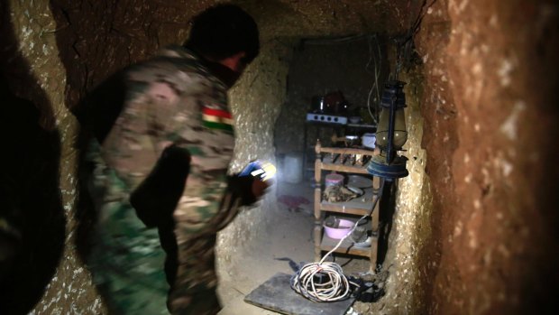 A Peshmerga fighter walks through the kitchen of an underground tunnel made by Islamic State fighters. The Kurdish forces found the tunnel on Tuesday  in the town of Badana.