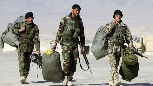 Afghan National Army soldiers carry their belongings at a military airport in Uruzgan province, Afghanistan, on Tuesday. 