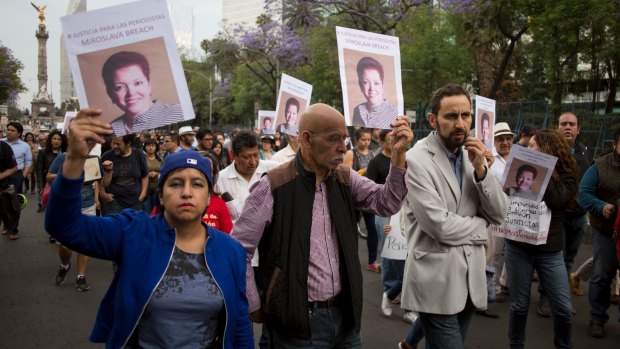 People hold up photos of Mexican journalist Miroslava Breach during a march in Mexico City.