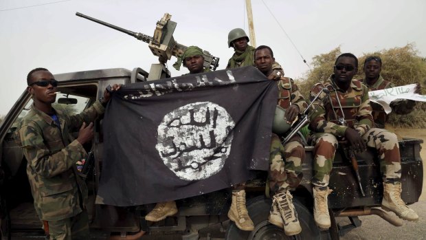 Nigerien soldiers hold up a Boko Haram flag that they had seized in the recently retaken town of Damasak, Nigeria.