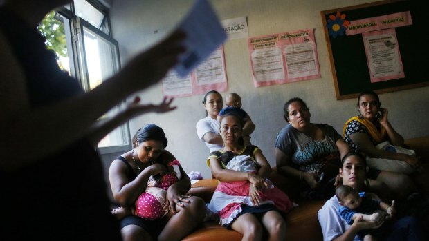 Infants born with microcephaly are held by mothers and family members as they listen to a speaker at a meeting for mothers of children with special needs in Recife on Thursday.