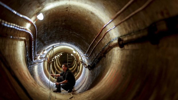 Electrician Glenn Kelly works in the 1890s ventilation tunnel under Victoria's Parliament House.