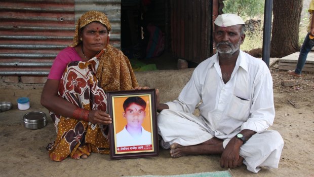 Bereft parents: Rekah and Raju Aage pose outside their home in Kharda with a portrait of their son, Nitin.