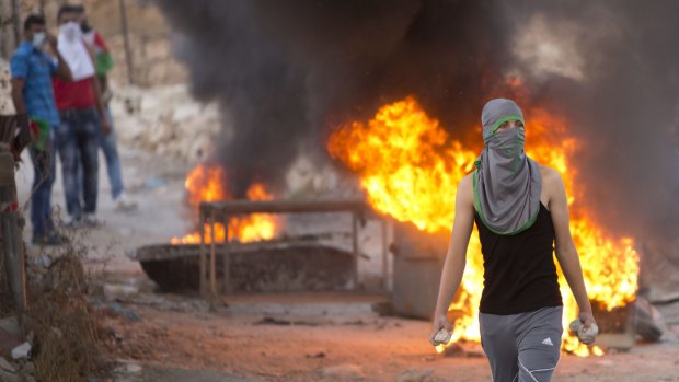 A Palestinian demonstrator holds rocks during clashes with Israeli security forces, at Hizme checkpoint. 