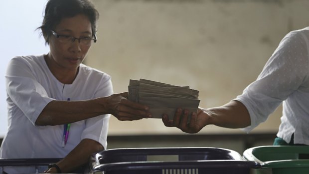 An official of the Union Election Commission hands over a stack of ballots to another at a polling station in Mandalay, Myanmar, on Sunday.
