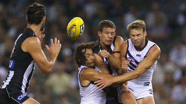 Luke Ball is crunched by Tendai Mzungu and Paul Duffield during the Collingwood-Fremantle round 1 game in 2014.