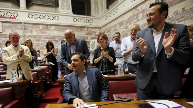 Greek Prime Minister Alexis Tsipras (seated) is applauded by his colleagues in the ruling Syriza party inside the Greek parliament.