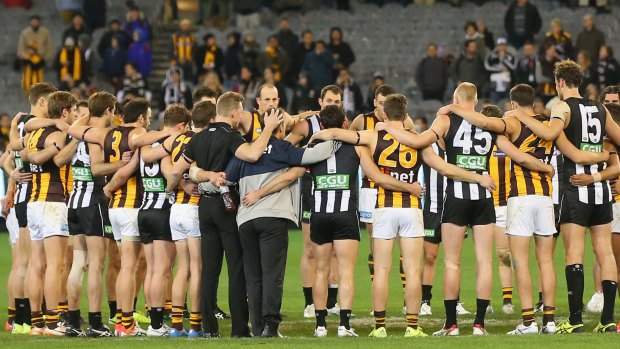 Hawthorn and Collingwood players stand in a circle after the game to pay tribute to Phil Walsh.