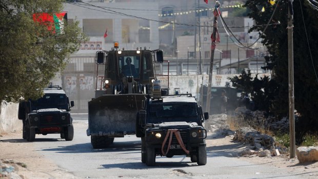 Israeli security forces and a military bulldozer raid the occupied West Bank village of Deir Abu Mashal near Ramallah on Saturday after the Jerusalem attack.