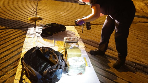 Officers examine drugs seized from a dinghy as it moored in Parsley Bay on the NSW Central Coast.