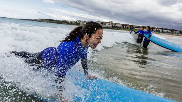 A Chinese visitor gets a surfing lesson at Bondi Beach.