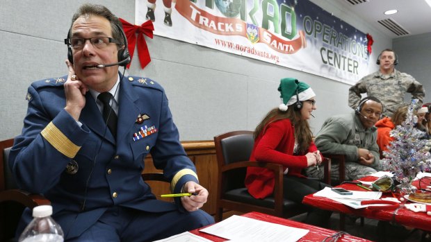 Canadian Brigadier General Guy Hamel, left, joins other volunteers taking phone calls from children around the world asking where Santa is.