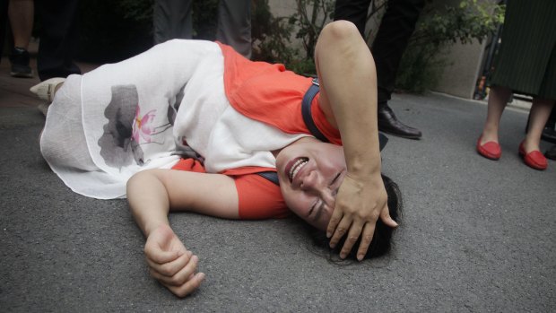 Fan Lili, the wife of imprisoned activist Gou Hongguo, lies on the ground after being knocked over by plainclothes officers outside the Tianjin No. 2 Intermediate People's Court on Monday.