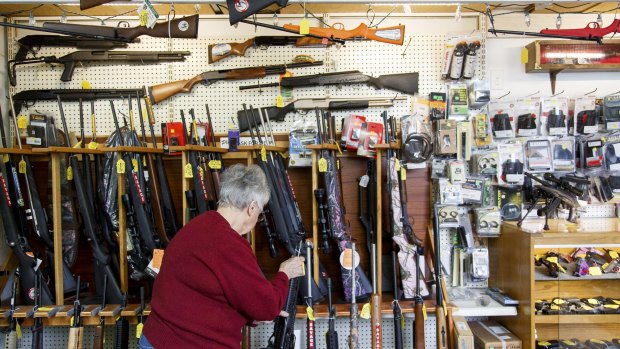 Carolyn Kellim, the owner of KC's Exchange, rearranges guns on a shelf in Roseburg, Oregon, scene of the mass shooting recently.