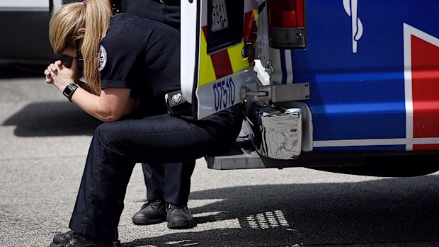 An ambulance driver rests her head on her hands outside North Park Elementary School after a fatal shooting at the school.