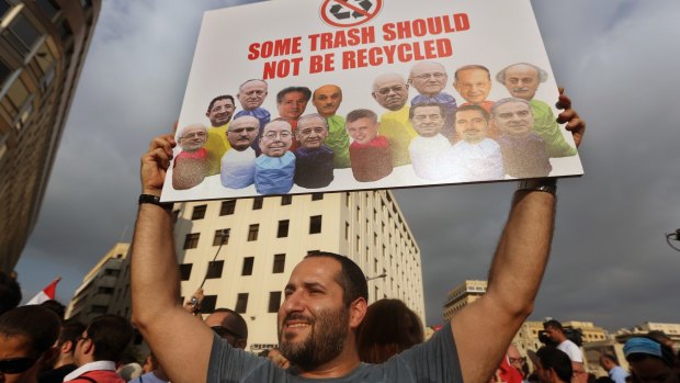 A Lebanese activist holds a poster with pictures of leading Lebanese politicians.