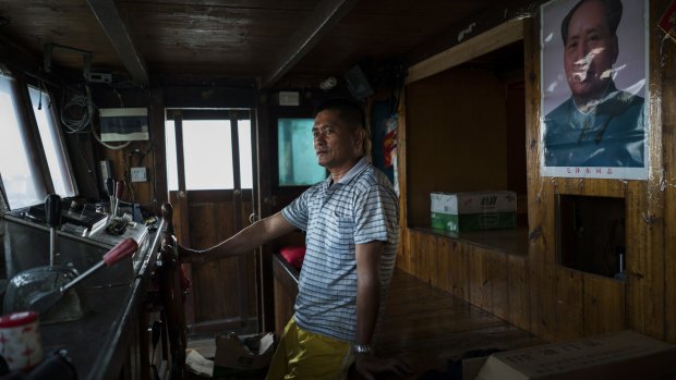 Captain Chen Yuguo watches his boat's refitting from the wheelhouse of his trawler - which has a poster of Mao Zedong and an expensive navigation system supplied by the government - before heading back out to fishing grounds near the Spratly Islands.