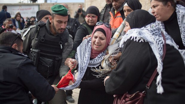 Israeli police officers try to remove a Palestinians flag from women protesting outside the Damascus Gate in Jerusalem Old City.