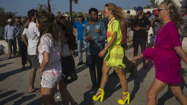 Tourists walk past migrants from Afghanistan, Syria, Iran, Bangladesh and Pakistan on the Greek island of Kos this week. 
