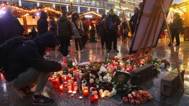 A visitor lays a candle at a makeshift memorial inside the reopened Breitscheidplatz Christmas market.
