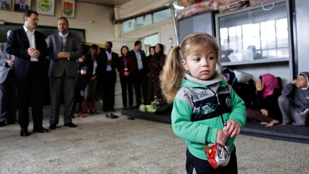 A girl holds a snack at a school in the Yarmouk refugee camp during the visit of UN official Pierre Kraehenbuehl on Sunday.