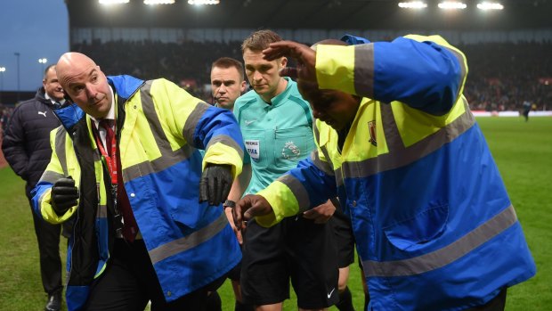 Crowd trouble: Referee Craig Pawson is escorted off at half time by stewards.
