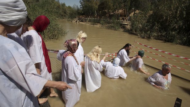 Orthodox Christian pilgrims line up to be baptised by their priest in the waters of Jordan River at Qasr el Yahud.