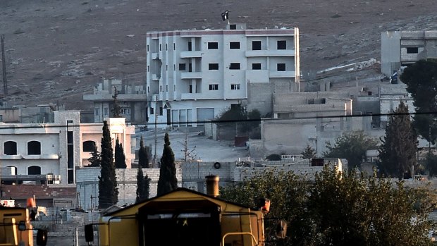 ATTACK SIGNAL: Islamic State militants raise their flag on a building on the eastern edge of Kobane.