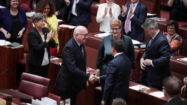 Attorney-General George Brandis shakes hands with Liberal senator Dean Smith as the bill passes the Senate.