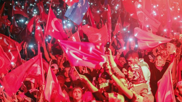 Turkish people wave flags and use their mobile phone torches during a speech by President Erdogan in August when he promised to fight those who seek to undermine the government.