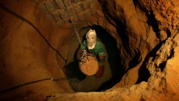 A Palestinian tunnel digger, wearing a mask to conceal his identity, removes sand in a bucket from a tunnel underground in Rafah, in the southern Gaza, in 2007.