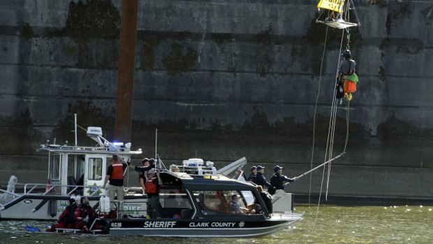 An activist who was hanging from the St Johns Bridge in an effort to block the  Royal Dutch Shell PLC icebreaker Fennica from leaving for Alaska is hauled in by law enforcement after he was lowered from his position in Portland on Thursday. 
