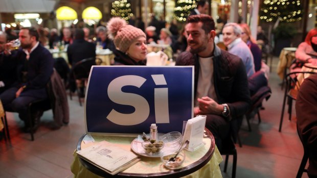 'Yes' campaign supporters eat dinner behind a poster in Florence on Friday.