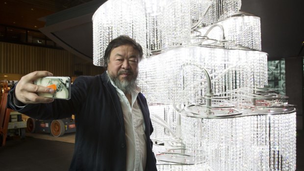 Ai Weiwei takes a selfie at the National Gallery of Victoria in front of his work Chandelier with Restored Han Dynasty Lamps for the Emperor, 2015, part of the exhibition Andy Warhol|Ai Weiwei.