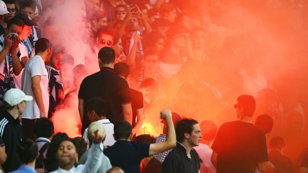 A flare is ignited in the Melbourne Victory supporters area of the crowd.