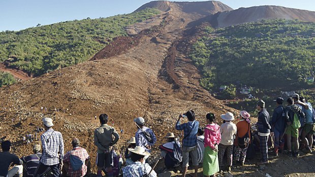 People look over an area covered by a landslide at Phakant jade mine, Kachin State, Myanmar on Saturday. Over 113 bodies have been recovered and 100 miners are still missing, according to officials.