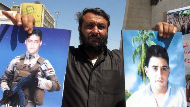 An Iraqi man holds posters bearing the portraits of his relatives, who are believed to have been killed by Islamic State in 2014 in the so-called Camp Speicher massacre.