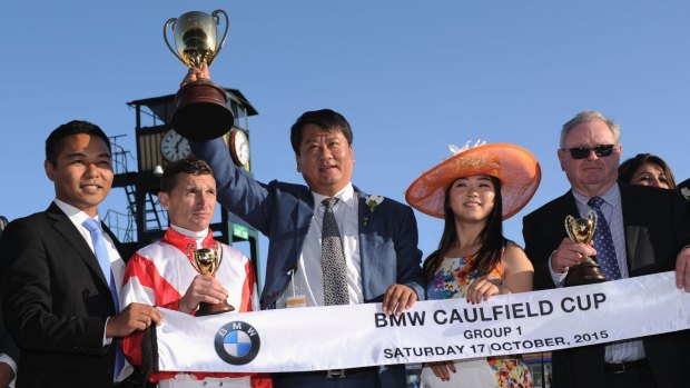Winning owner Lin Lang poses with the trophy  and jockey Opie Bosson after Mongolian Khan won the Caulfield Cup.