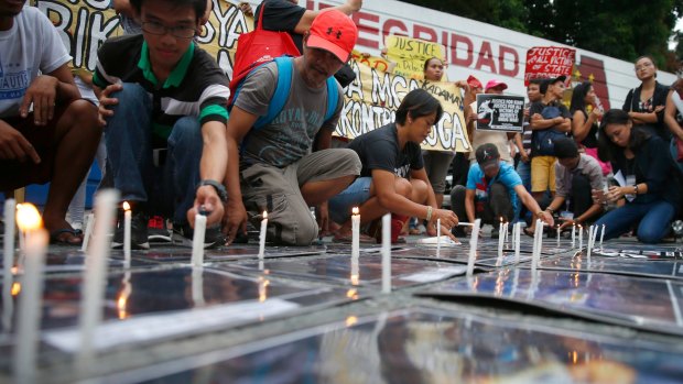 Protesters light candles on photos of alleged victims of extra-judicial killings during a rally outside the Philippine National Police headquarters on Wednesday.
