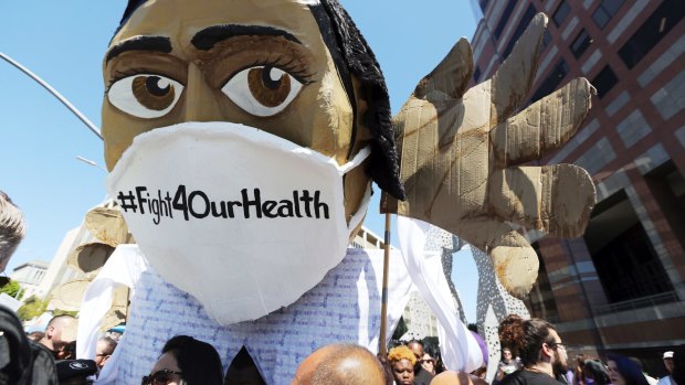 An oversize effigy of a health care professional is seen as hundreds of people march through downtown Los Angeles protesting President Donald Trump's plan to dismantle Obamacare.