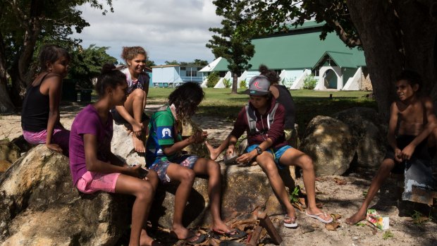 Children crack open nuts from a nearby tree in Yarrabah. 