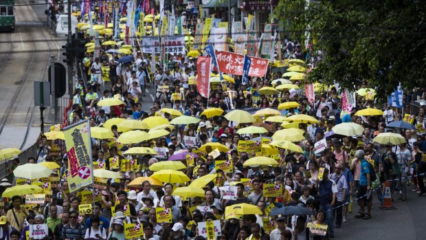 Protesters carrying yellow umbrellas and signs march during a pro-democracy rally in Hong Kong on Sunday.