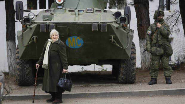 An elderly ethnic Armenian woman stands next to a Russian peacekeeper's APC in Berdzor in the separatist region of Nagorno-Karabakh.