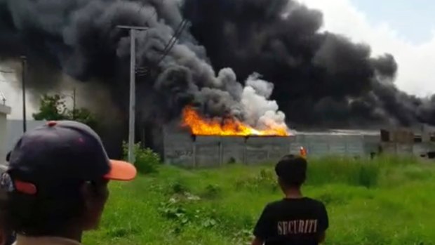 Residents watch as thick black smoke billows from the site of an explosion at a firecracker factory in Tangerang, Indonesia, on Thursday.