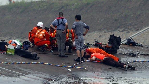 Chinese rescue workers use listening devices to detect survivors inside the capsized vessel.