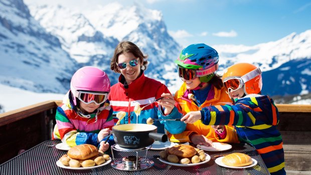 Family enjoy an apres ski lunch with traditional Swiss raclette and cheese fondue.