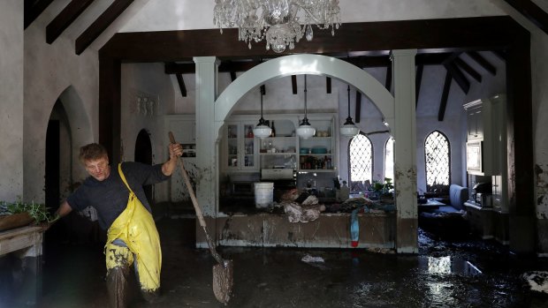 Bill Asher walks through mud in his home damaged by storms in Montecito, Calif.